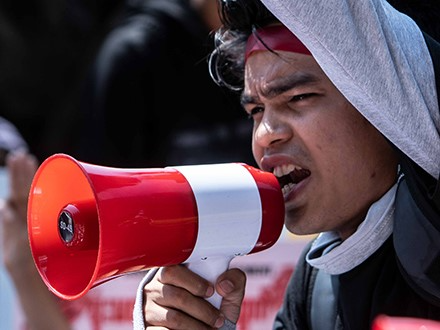 A protestor speaks through a speakerphone