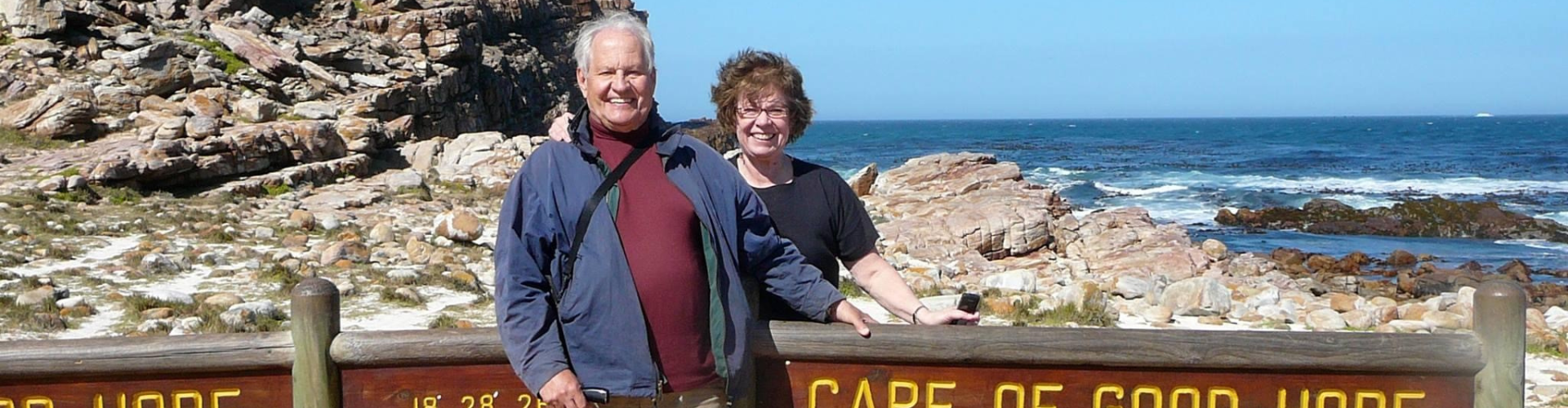 Carol Larson and her husband stand by a sign at Cape Cod